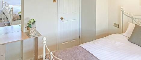 Un dormitorio con cama, mesita de noche y espejo.