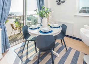 Ein Essbereich mit einem runden Tisch, Stühlen und einer Vase mit Blumen.