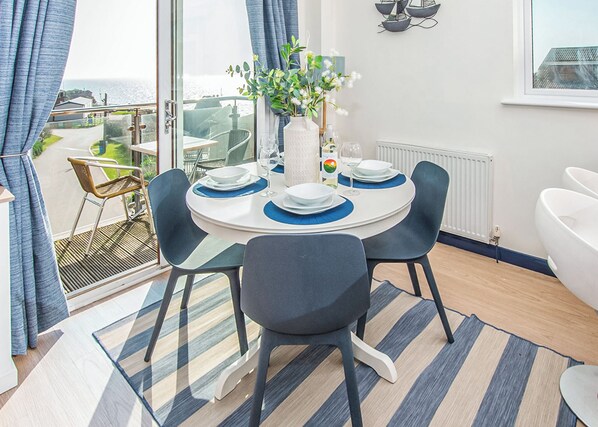 A dining area with a round table, chairs, and a vase with flowers.