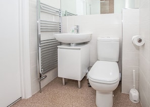 Ein kleines Badezimmer mit einem weißen Waschbecken, einer Toilette und einem Handtuchhalter.