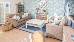 Een woonkamer met een bank, salontafel en een decoratieve wand met een nautisch thema.