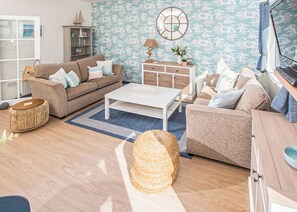 A living room with a sofa, coffee table, and a decorative wall with a nautical theme.