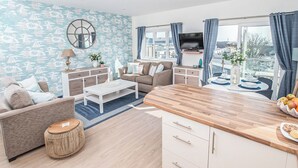 Een moderne woonkamer met een bank, salontafel en een houten keukeneiland met fruit.