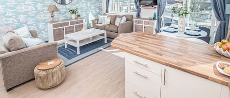 A modern living room with a sofa, coffee table, and a wooden kitchen island with fruit.