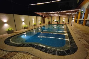 An indoor swimming pool with a tiled edge, surrounded by potted plants and a pergola with string lights. - Veda Hotels & Villas (Marra)