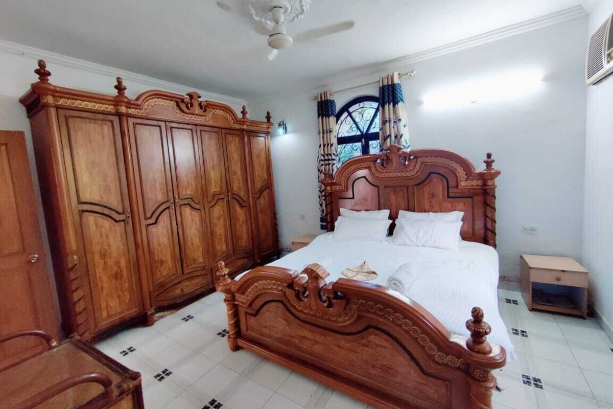 A bedroom with a wooden bed, wardrobe, and ceiling fan.