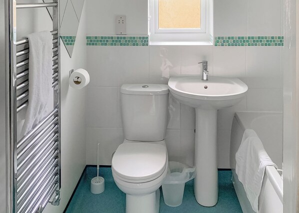 A bathroom with a toilet, sink, and towel rack.
