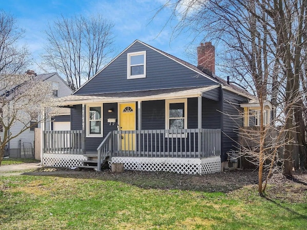 A two-story house with a porch, a chimney, and a small front yard.