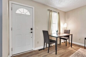 A dining area with a table and chairs, a white door with a window, and a lamp.