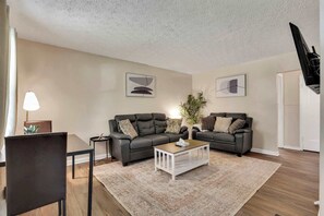 A living room with two sofas, a coffee table, a lamp, and a TV. - The Columbus Garden Retreat | 5Beds One Level Home (Columbus)