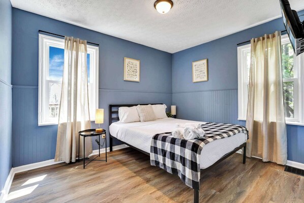 A bedroom with a bed, curtains, a bedside table, and a window. - The Columbus Garden Retreat | 5Beds One Level Home (Columbus)