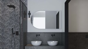 Ein modernes Badezimmer mit zwei weißen Waschbecken, einem großen Spiegel und einer Duschkabine.