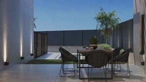 Eine moderne Außenpatio mit Tisch, Stühlen, einem Blumentopf und Blick zum Himmel.