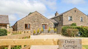 Une petite maison en pierre avec un portail en bois portant l’inscription « Dairy Cottage ».