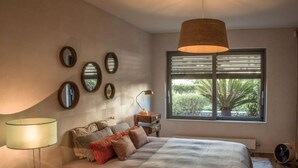 Ein Schlafzimmer mit einem Bett, Nachttischlampen, einem Fenster mit Jalousien und einer Deckenleuchte.