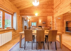 A wooden cabin interior with a dining area, a sofa, and a fireplace. - Spacious and comfortable lodge with contemporary styling. (Ellesmere)