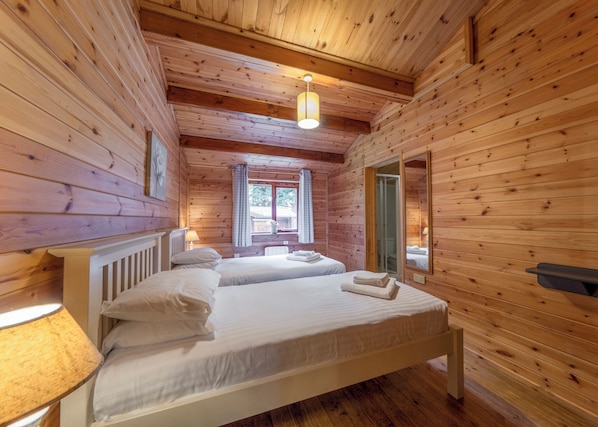 Ein Zimmer einer Holzhütte mit zwei Betten, einem Fenster und einem Spiegel.