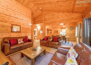 A wooden cabin interior with a living room, dining area, and a visible door leading to another room. - Spacious and comfortable lodge with contemporary styling. (Ellesmere)