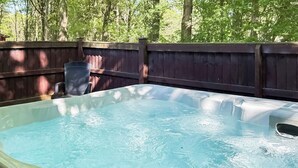 A hot tub in a backyard with a wooden fence and trees in the background. - Spacious and comfortable lodge with contemporary styling. (Ellesmere)