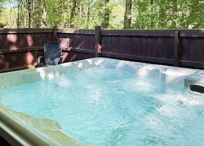 A hot tub in a backyard with a wooden fence and trees in the background. - Spacious and comfortable lodge with contemporary styling. (Ellesmere)
