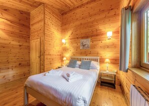Ein Zimmer mit Holzwandverkleidung, einem Bett, Nachttischlampen und einem Fenster.