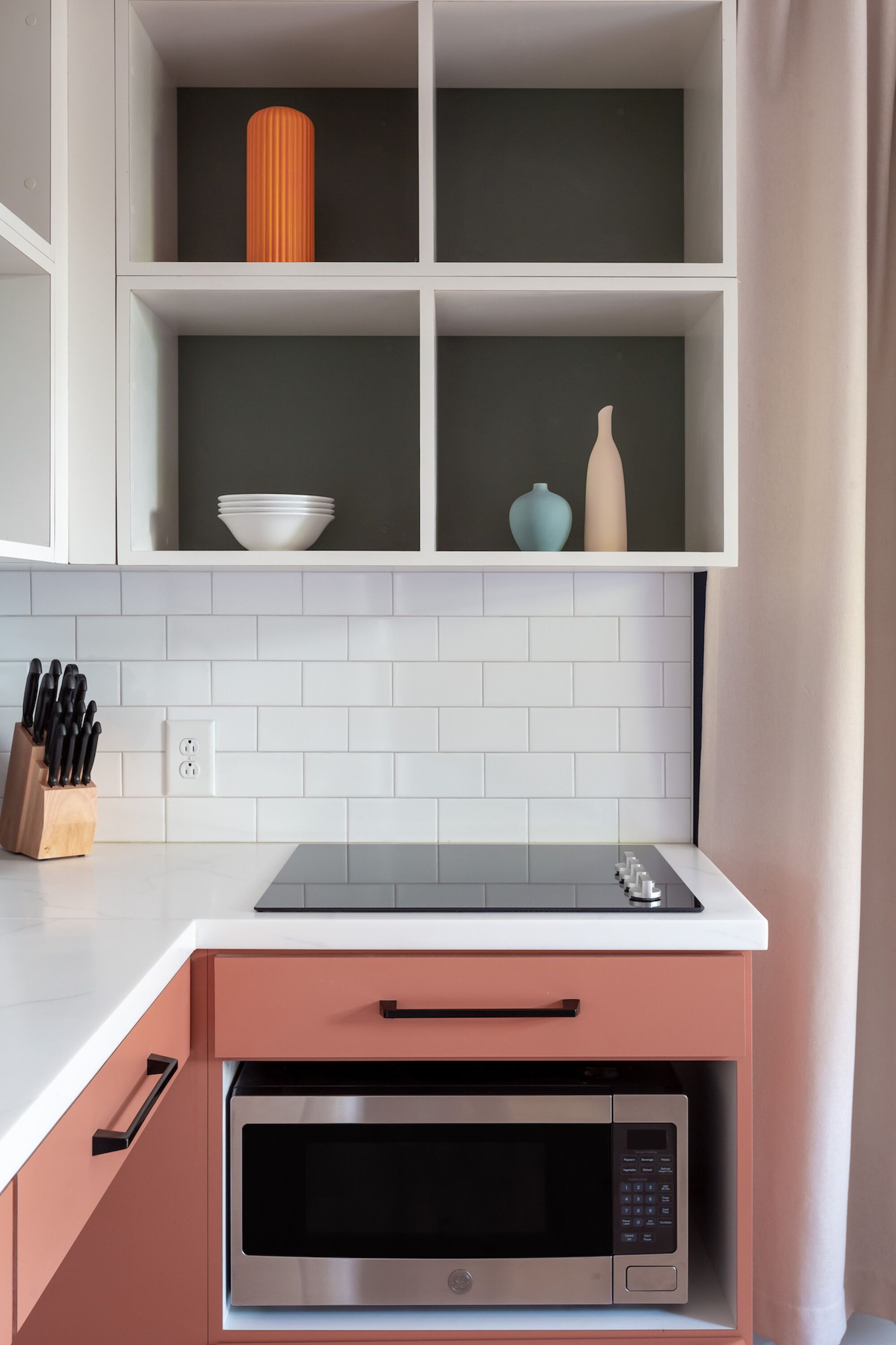 A kitchen with white cabinets, a microwave, and a countertop with a knife block.