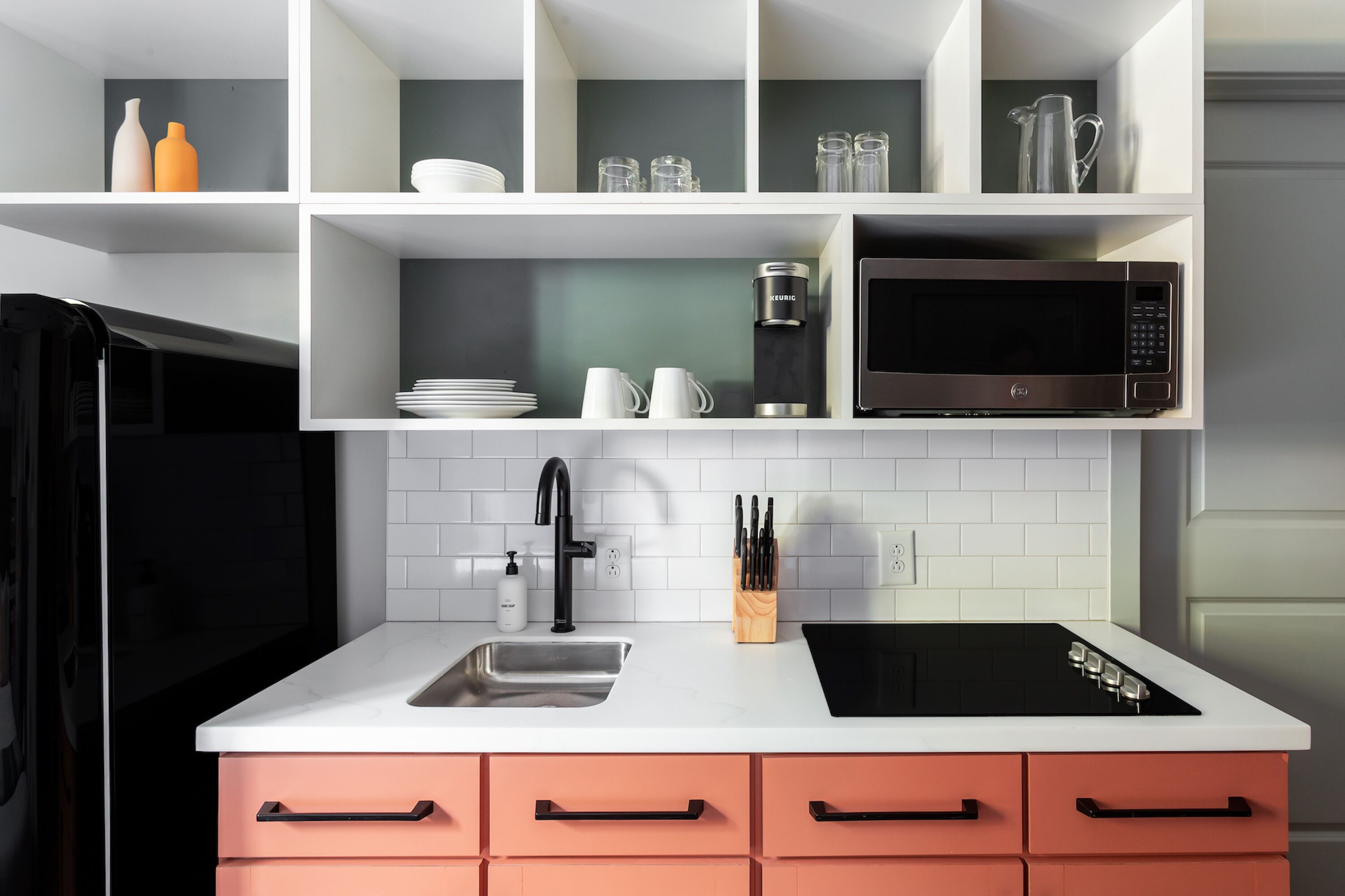 Una cocina moderna con armarios blancos, una estufa negra, un fregadero y un microondas.