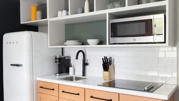A modern kitchen with white cabinetry, a built-in microwave, a sink, and a coffee maker.