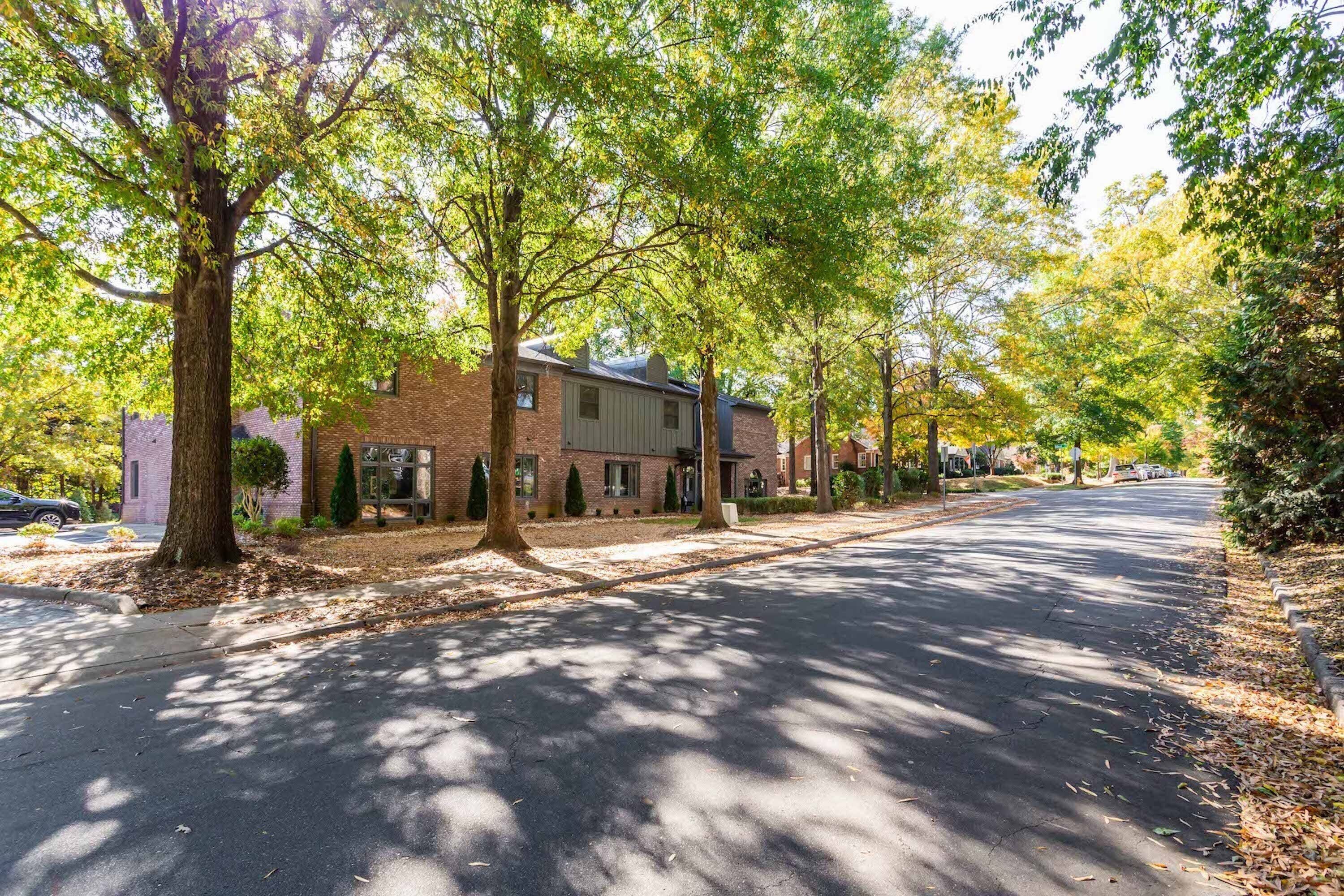 A quiet residential street lined with mature trees and brick houses.