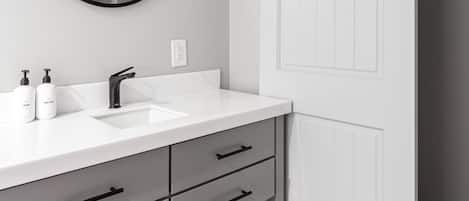 A modern bathroom with a white vanity, black fixtures, and a sliding door.