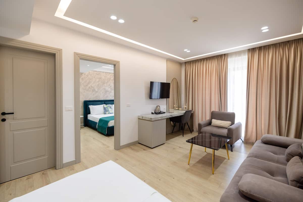 A modern hotel room with a bed, desk, TV, and seating area.