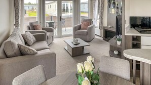 Ein modernes Wohnzimmer mit einer Couch, Sesseln, einem Couchtisch und einer Rosenvase.