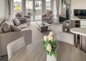 A modern living room with a sofa, armchairs, a coffee table, and a vase of white roses.