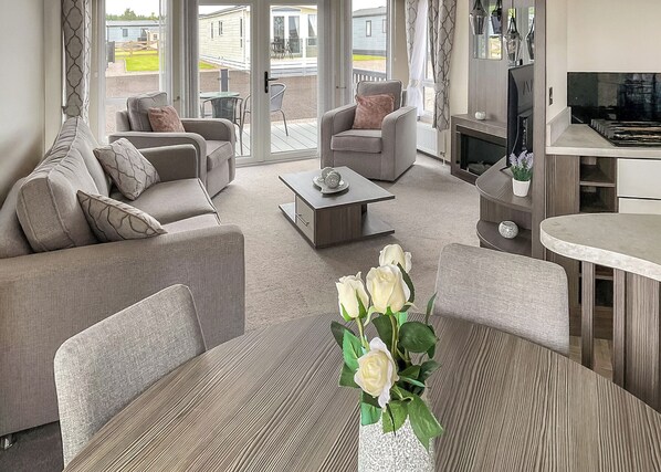 Ein modernes Wohnzimmer mit einer Couch, Sesseln, einem Couchtisch und einer Rosenvase.