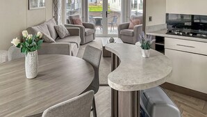 Eine moderne Küche mit einer gewölbten Kücheninsel, einem Essbereich mit rundem Tisch sowie einer Sitzecke mit Sofas und Sesseln.