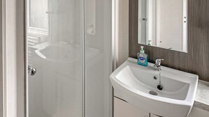 A bathroom with a glass shower door, a white sink with a mirror, and a bottle of Carex hand soap. - Spacious and comfortable holiday home featuring your own private hot tub. (Laurenkirk)