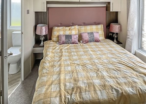 Un dormitorio con cama, lámparas de noche, cabecero y ventana.