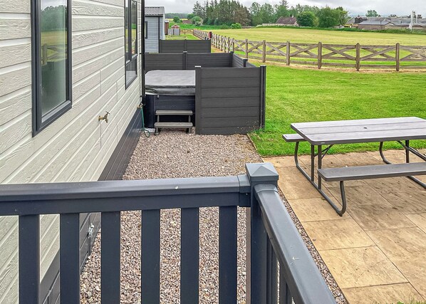 A patio area with a wooden deck, a bench, and a picnic table.