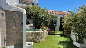 A residential property with a stone shower, a small pool, and a well-maintained lawn.