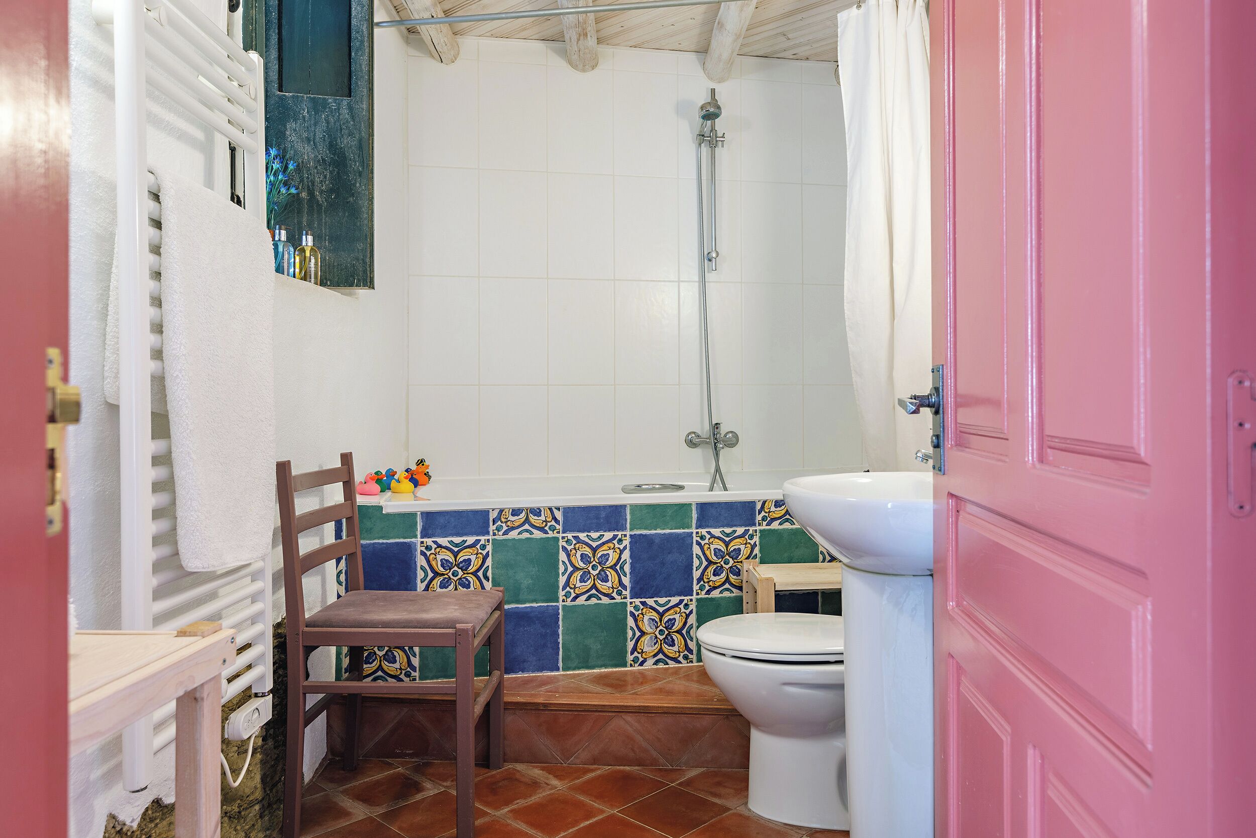 Un baño con ducha, inodoro y una silla.