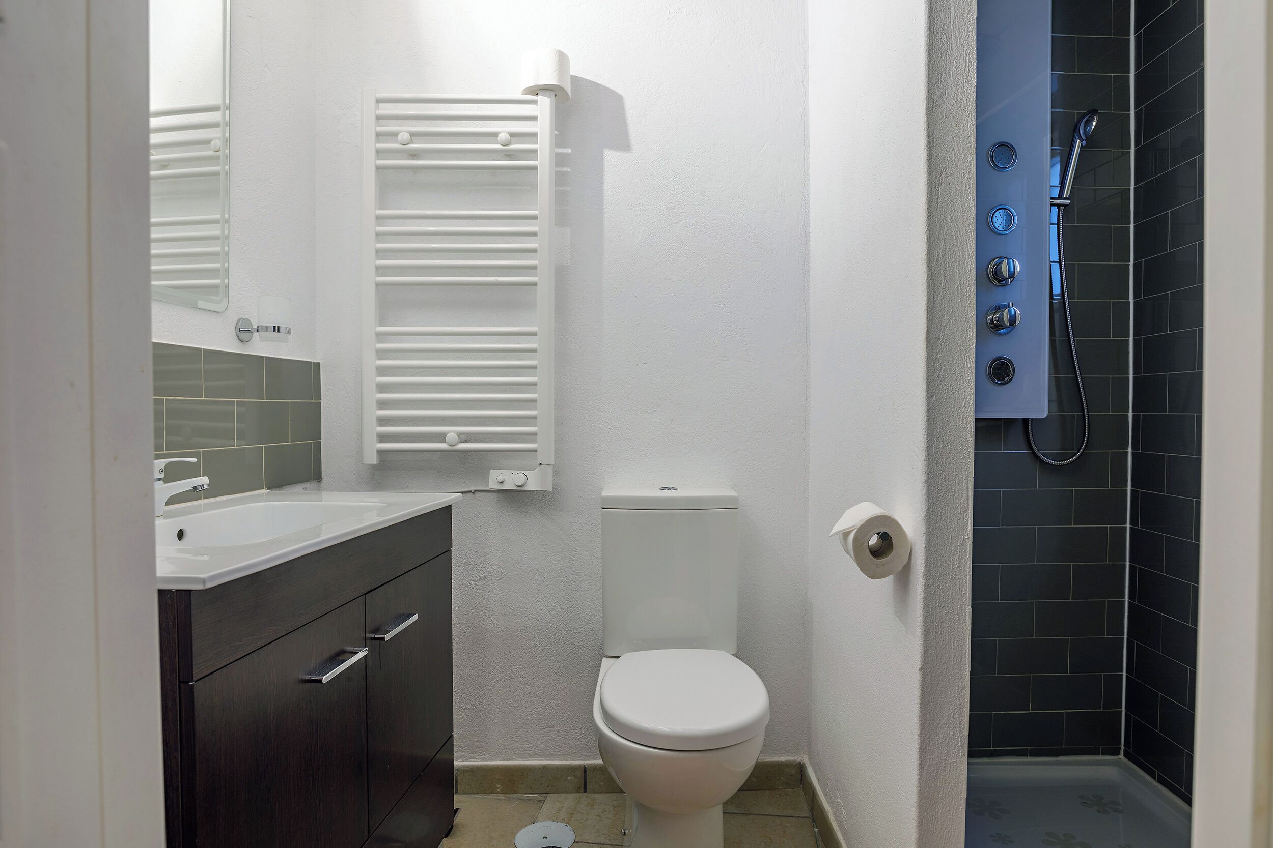 A small bathroom with a toilet, a sink, a towel rack, and a shower.