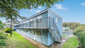 Ein zweistöckiges Gebäude mit flachem Dach, einer Treppe auf der rechten Seite und einem Balkon im oberen Geschoss.
