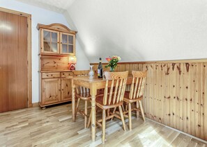 Ein Holzespeisesaal mit Stühlen, einem Schrank und einer Vase mit Blumen.