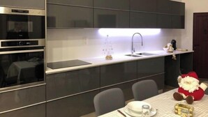 A modern kitchen with dark cabinetry, a built-in oven, and a stainless steel sink. - Modernly Equipped Country House, 5 minutes from Natural Swimming Pools (Altares)