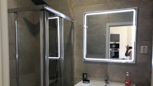 A modern bathroom with a glass-enclosed shower, a white sink, and a mirror with integrated lighting. - Modernly Equipped Country House, 5 minutes from Natural Swimming Pools (Altares)