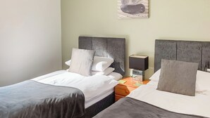 A hotel room with two beds, a nightstand, a lamp, and a wall-mounted picture. - Luxury lodge residing at the top of the wooded valley. (Waterrow, Wiveliscombe)