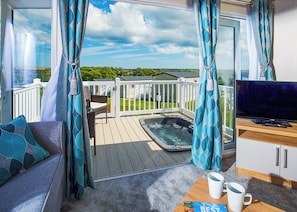 A balcony with a hot tub, a TV, and a sofa with cushions.