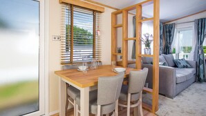 A dining area with a wooden table and chairs, a window with blinds, and a view of the outdoors.