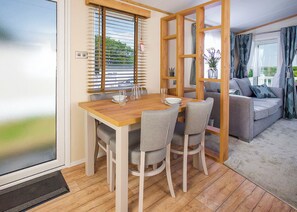 A dining area with a wooden table and chairs, a window with blinds, and a view of the outdoors.