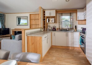 A compact kitchen with wooden cabinets, a built-in microwave, and a stove.